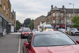 A seagull perched on the roof of a red Mercedes estate car on James Street in Helensburgh