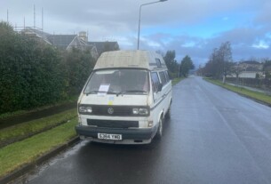A white Volkswagen camper van parked by the side of the road